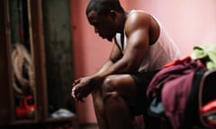 A black man sits alone with his head bowed