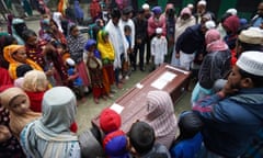 A group of mourners around a coffin at a funeral