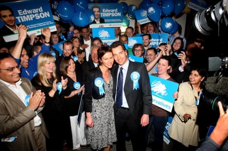 Timpson and his wife stand with a crowd of supporters who are holding election campaign placards.