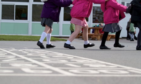 A line of schoolchildren play on a school playground, photo cropped so their heads are not visible