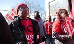 Black woman in crowd wearing matching red T-shirts.