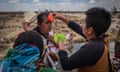 A man takes off his hat as another man applies water to his forehead in a blessing