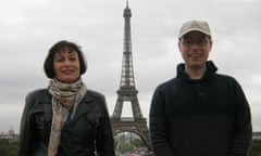 A man and a woman smiling for a photo, with the Eiffel Tower in the background.