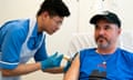 A nurse holding a syringe gives a man an injection