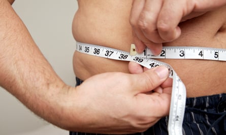 Close-up of man measuring waist with tape measure