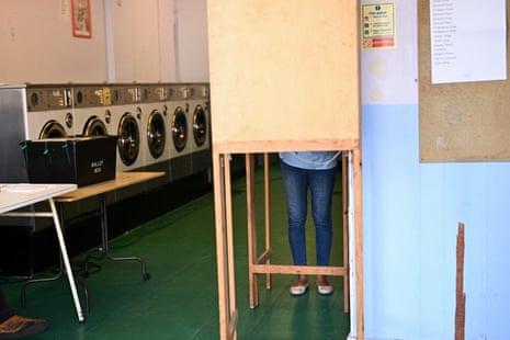 A person votes inside a polling station at a launderette in Headington, Oxford.