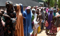 Women carrying children queue outside a clinic