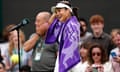 Emma Raducanu wearing a purple Wimbledon towel and laughing beside a microphone stand on court