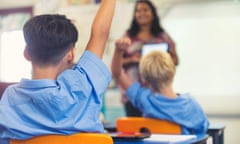 An Aboriginal school teacher giving a presentation to a class. The students have their hands raised to ask questions