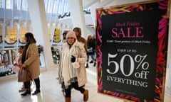 People at a shopping mall in front of a Black Friday sign offering 50% off.