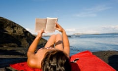 Woman reading book on the beach with sea below the sky in the background<br>C5C17F Woman reading book on the beach with sea below the sky in the background