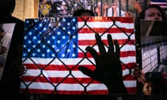 Hand holding fence, american flag in the background