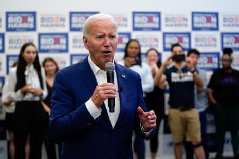 a man in a suit speaks into a microphone surrounded by people