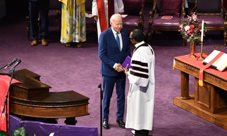 white man wearing suit shakes hand of Black man wearing white outfit