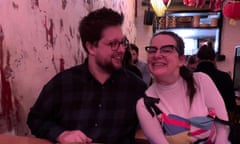 A man and woman sitting next to each other in a dumpling restaurant, bathed in a gentle pink light.