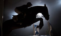 Silhouette of a horse and a rider jumping over hurdle