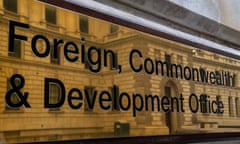 A brass sign reading Foreign, Commonwealth & Development Office shows a reflection of a brick building.