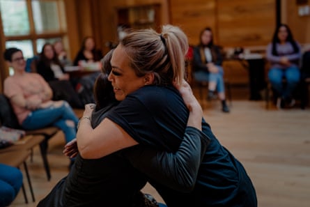 Two women embrace in a round table.