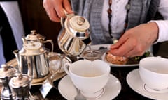 Woman pouring tea through a strainer from teapot at  Bettys  in Harrogate