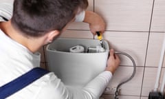 Plumber repairing toilet cistern at water closet<br>2BJDEG5 Plumber repairing toilet cistern at water closet