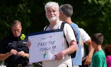 white man wearing white shirt holds sign