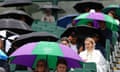 Tennis fans shelter under umbrellas at Wimbledon this month