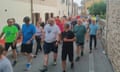 Luciano Fregonese in a white shirt and navy blue shorts walking with a group of local people.