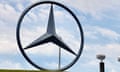 Very large metal Mercedes Benz symbol, a three-pointed star inside a circle, under partly cloudy sky.