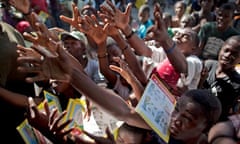 People reach out to catch books, donated by the Cuban government in Port-au-Prince, Haiti