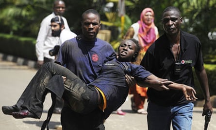A Kenyan woman is helped to safety after shootings in a Nairobi shopping mall