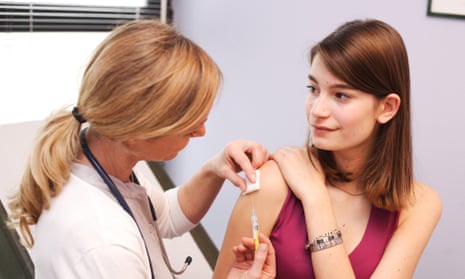 Female teenager receiving a vaccination from a doctor during medical consultation.