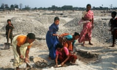 Indian women and children work as stone crushers.