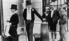 Local lads look on with curiosity at Harrow schoolboys in 1937