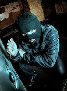 Robber and the car thief in a mask opens the door of the car and hijacks the car.