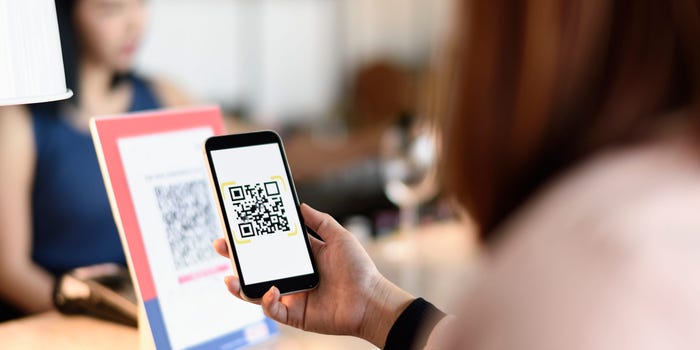 woman scanning QR code with smartphone at store