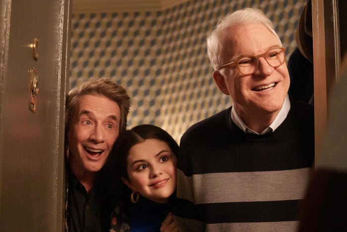 Oliver, Mabel, and Charles smile in a doorway in this still from season 2 of Hulu's "Only Murders in the Building."