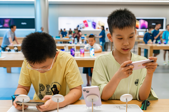 Two children hold iPhones at an Apple store