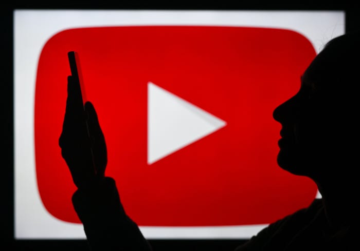 A silhouette of a woman holding up a smartphone sits in front of the YouTube logo, a red play button.