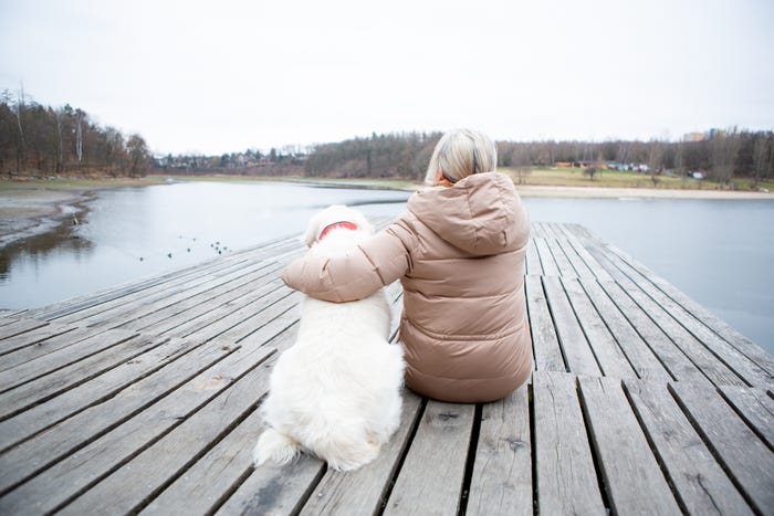 Older woman sitting on a dock with her dog.