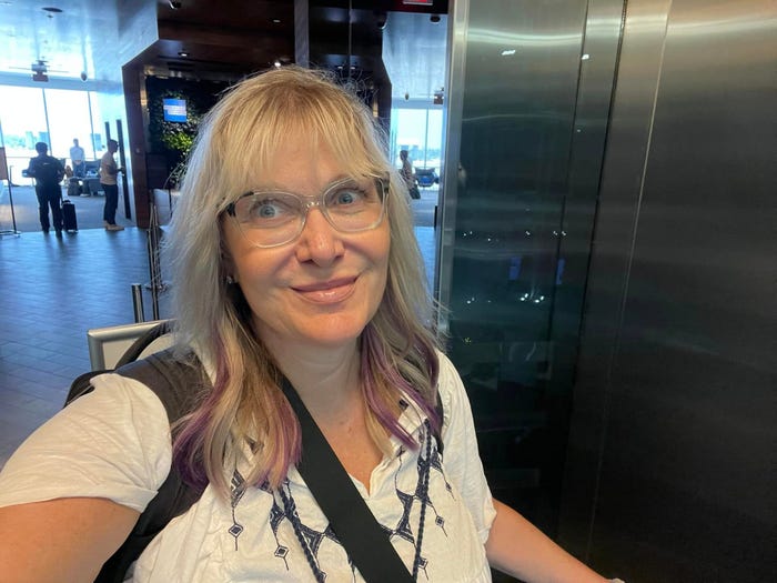 A woman wearing a backpack taking a selfie at an airport lounge.