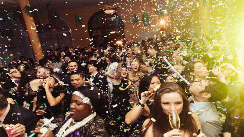 People celebrating at a party while confetti falls from the ceiling