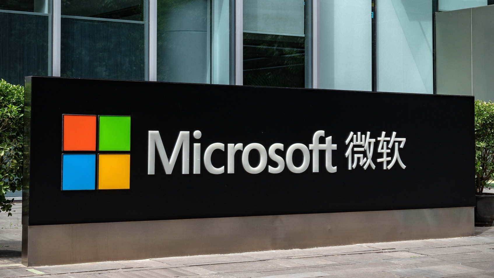 Microsoft sign with Chinese and English characters outside company's glass-walled Beijing office.