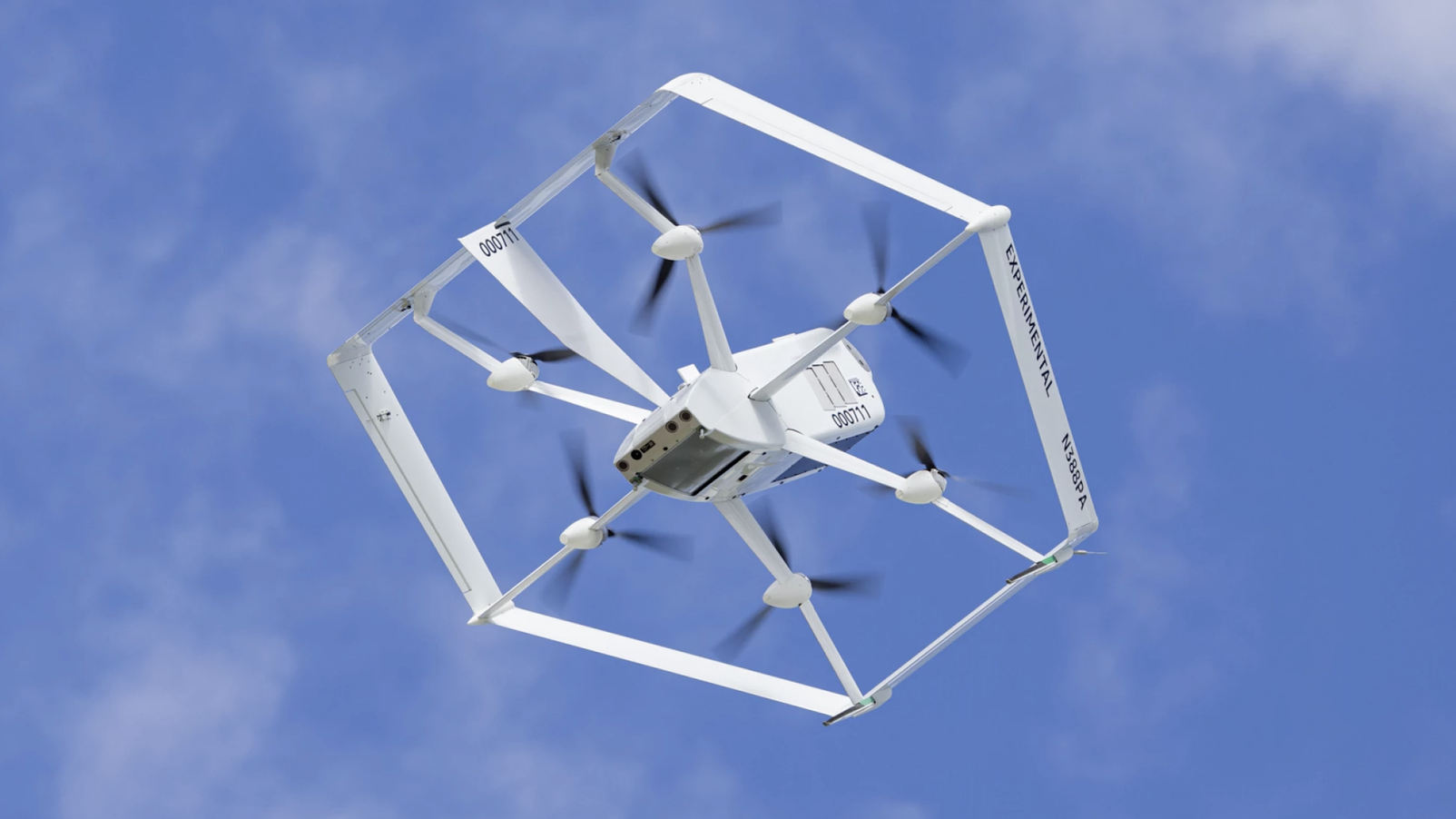 White Amazon MK-27 2 drone flying with blue sky and clouds behind. The drone is white and has 6 propellers.