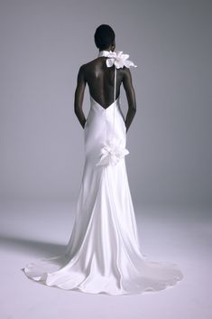 the back of a woman in a white dress with flowers on her neck and shoulders