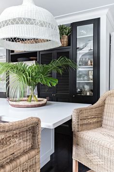 two wicker chairs sitting next to a table with a potted plant on it