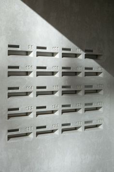 a metal wall with numbers on it in front of a white wall and a window