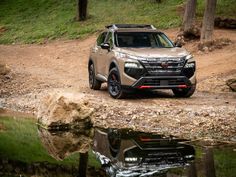 an suv is parked on the side of a dirt road next to a body of water