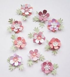 pink and green paper flowers arranged on white surface with one being cut out from the middle