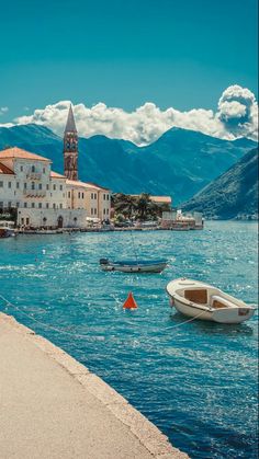 boats floating in the water near buildings and mountains