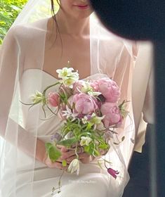 a woman in a wedding dress holding a bouquet of flowers